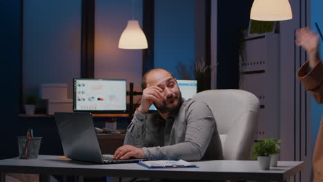 exhausted businessman checking marketing statistics on laptop computer