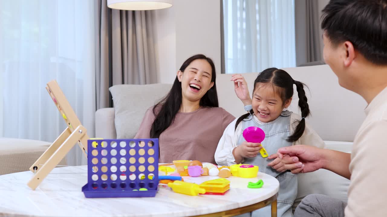 Asian family laughing and playing together with toys at home in bright natural daylight