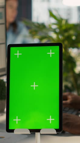 vertical video close up of green screen tablet in front of employee in office