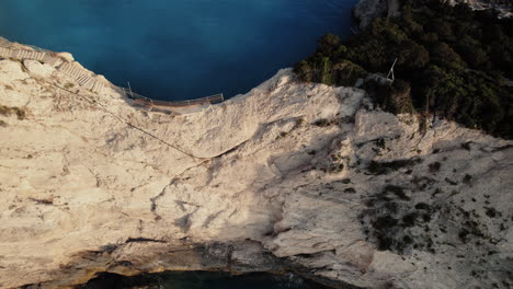 epic flip aerial drone shot over a rock in blue sea