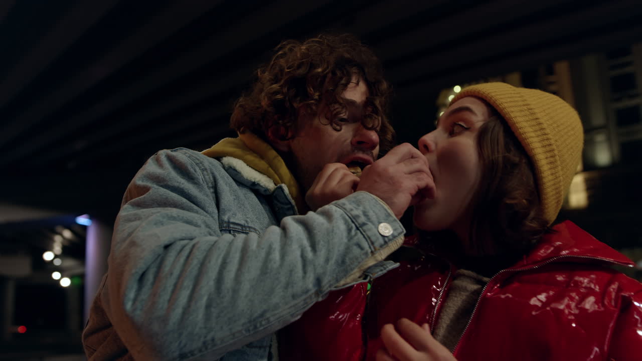 um casal alegre a alimentar-se ao ar livre. um homem e uma mulher a comer um lanche.