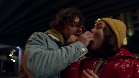 joyful couple feeding each other outdoor. man and woman eating snack food.