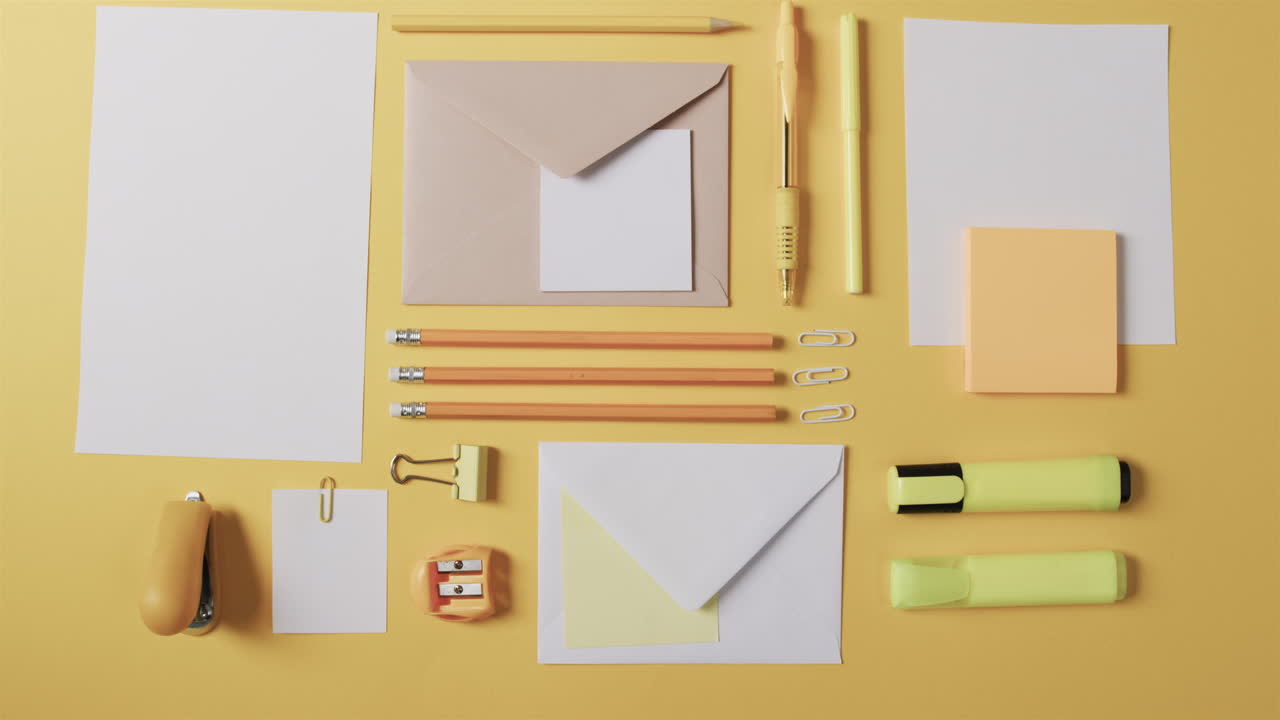 Assorted stationery items are neatly arranged on a yellow background