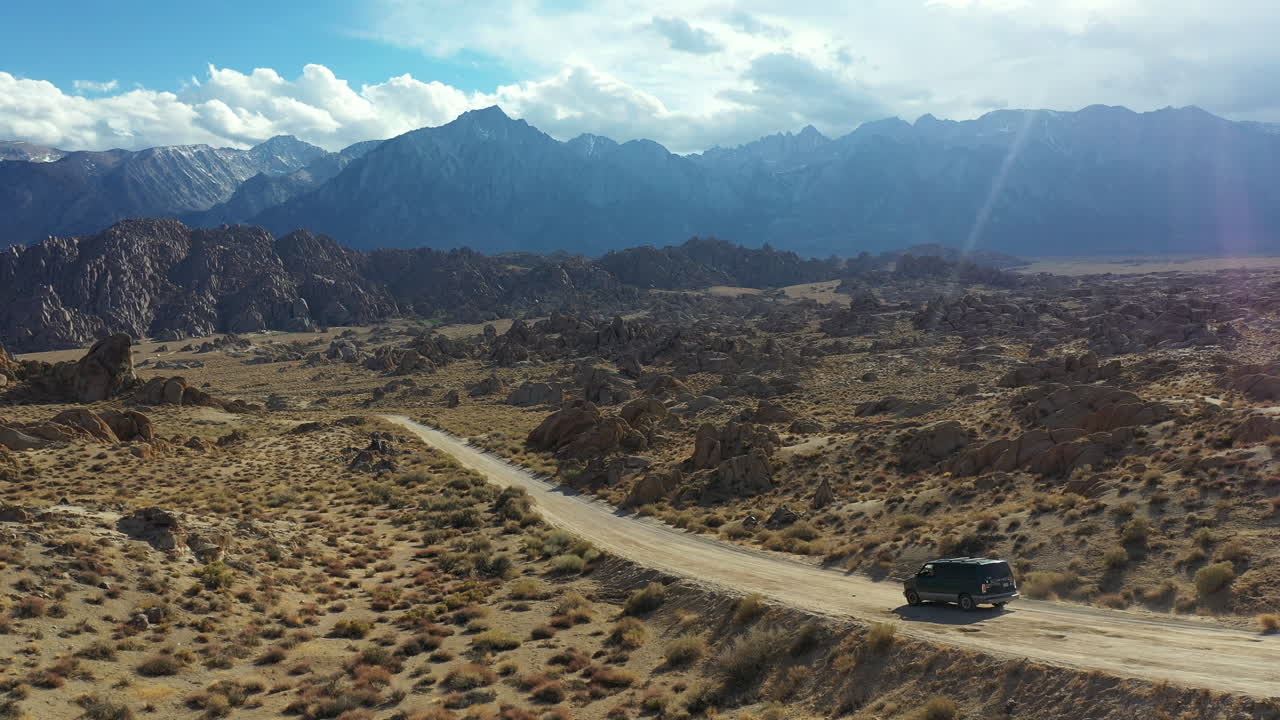 furgoneta oscura en la carretera del desierto, vista aérea de seguimiento cinematográfico del vehículo que se mueve en el paisaje seco de las colinas de alabama, california, ee.uu.