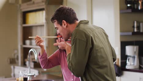 pareja feliz diversa preparando una comida juntos en la cocina, probando comida y riendo