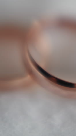 gold wedding rings pair on soft white fabric extreme closeup. glisten precious jewelry items for newlywed couple. bridal ceremony accessory