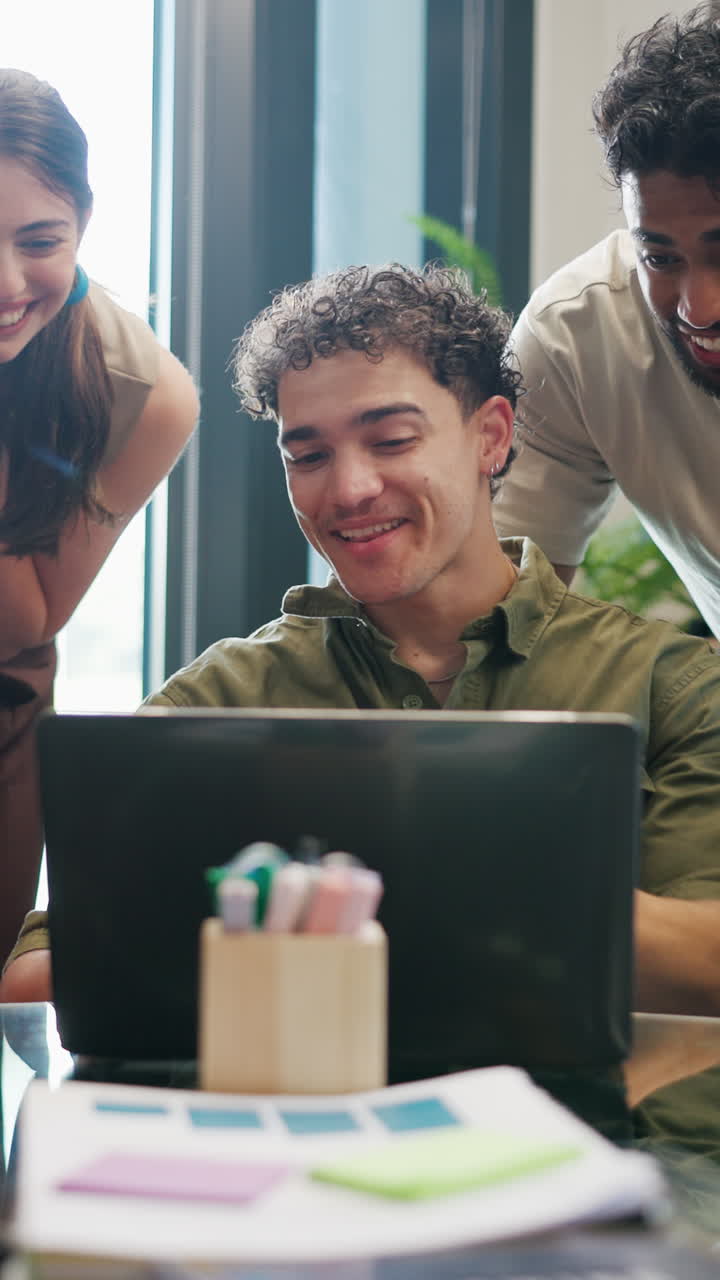 Young Professionals Collaborating and Smiling While Working on Laptop in Office