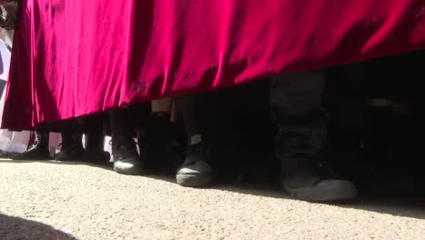 procession of people hidden behind red velvet cloth