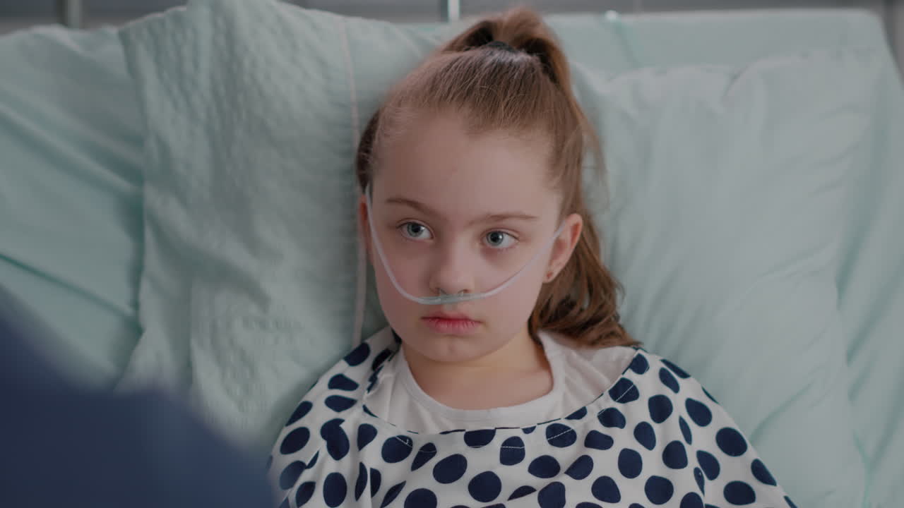 Close up of hospitalized sick daughter looking at father while resting in bed