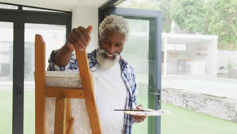 video of african american senior man painting picture outside