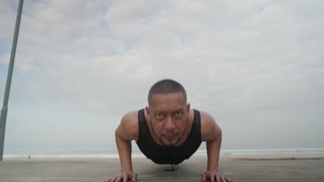 man doing push-ups on the beach