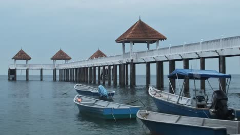 plano general estático de barcos de pesca estacionados y embarcadero vacío durante un día nublado en malasia