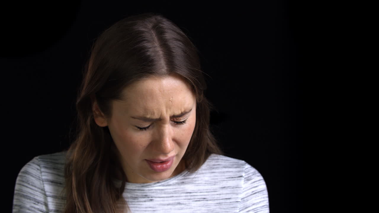 Studio Shot Of Scared Young Woman Flinching From Abuse