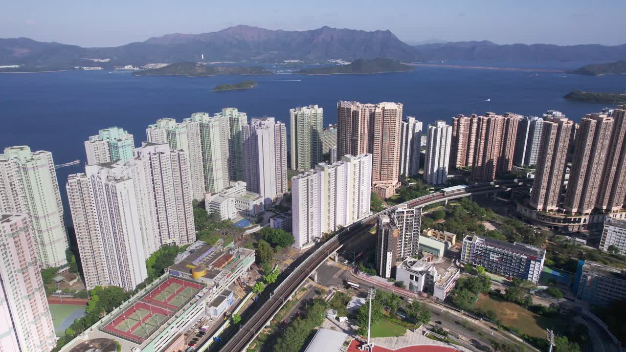 campo de fútbol y pista de atletismo entre los altos rascacielos poblados de vista paradiso mientras un tren se mueve sobre la vía férrea en hongkong