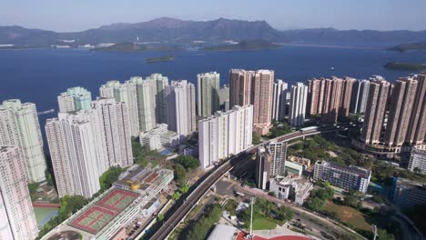 football field and running track between the high populated skyscrapers of vista paradiso while a train is moving over the railway track in hongkong