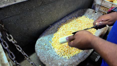 a dark-skinned man's hands cutting corn cobs.close up downward view
