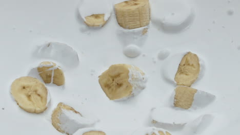 yogur de plátano fresco y cremoso con pedazos dulces caídos sobre una superficie blanca de cerca.