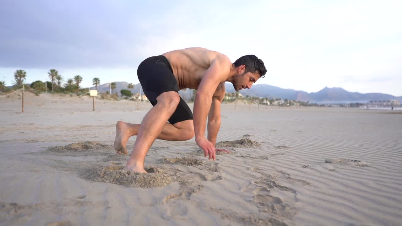 hombre haciendo ejercicios funcionales de suelo en la arena de la playa.