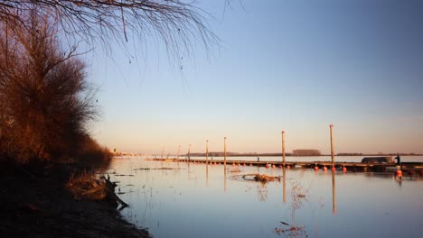 paseo marítimo de madera en el río danubio durante la puesta de sol cerca de la ciudad de galati en rumania