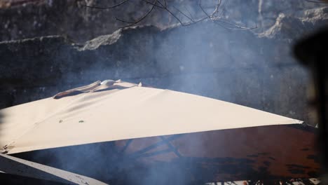 smoke drifts over an outdoor umbrella