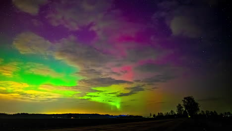 una toma de un time-lapse de una colorida aurora boreal en el cielo nocturno sobre el campo