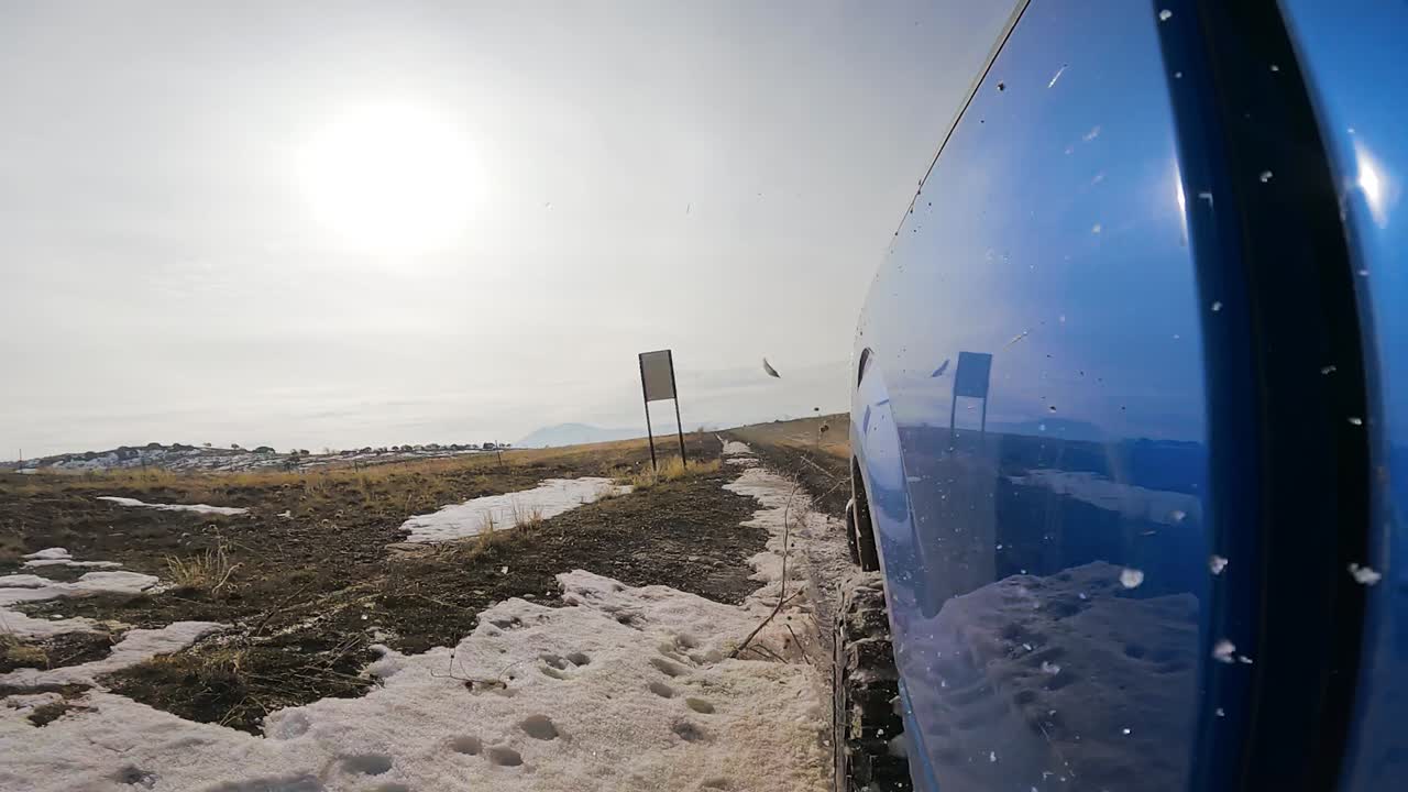 슬로우 모션으로 트럭 측면에서 볼 때 진흙과 눈이 날아다니는 흙길을 따라 운전