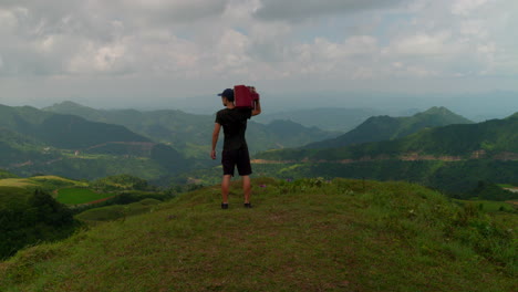 escena divertida de un hombre sosteniendo una vieja televisión en los hombros viendo el paisaje de la montaña