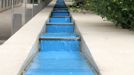 Water-Cascading-Down-A-Manmade-Blue-Step-Water-Feature,-TILT-UP