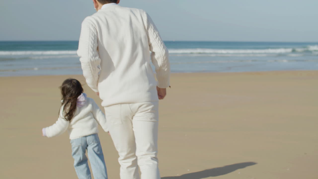 japanese father and little daughter running and playing game of tag at  seashore