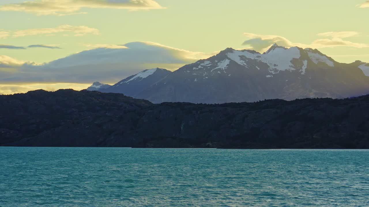 Static shot of Lake Belgrano with turquoise waters and the Andes mountains in the background illuminated by warm sunset light, in Perito Moreno National Park, Southern Patagonia, Argentina