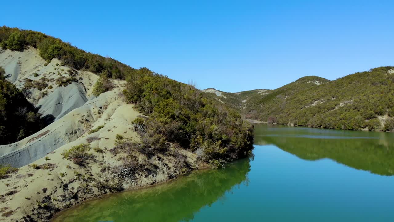Beautiful slopes of high mountains washed by calm clear water of lake reflecting bright blue sky, panoramic view