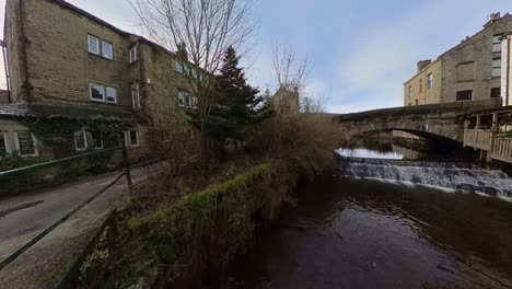 small waterfall on a river running through the town of delph near oldham, lancashire, uk