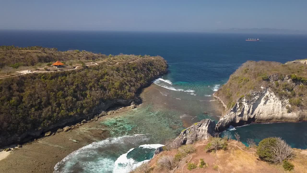 Luftaufnahme des Atuh Strandes auf Nusa Penida, Indonesien, an einem sonnigen Tag mit kristallblauem Wasser, das auf die Felsformationen trifft.
