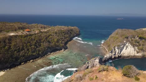 Aerial-view-of-Atuh-beach-on-Nusa-Penida,-Indonesia-on-a-sunny-day-and-with-crystal-blue-water-hitting-the-rock-formations