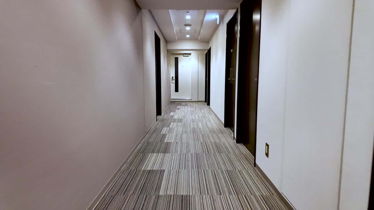 Point of view of someone walking down a deserted hotel corridor with doors on both sides