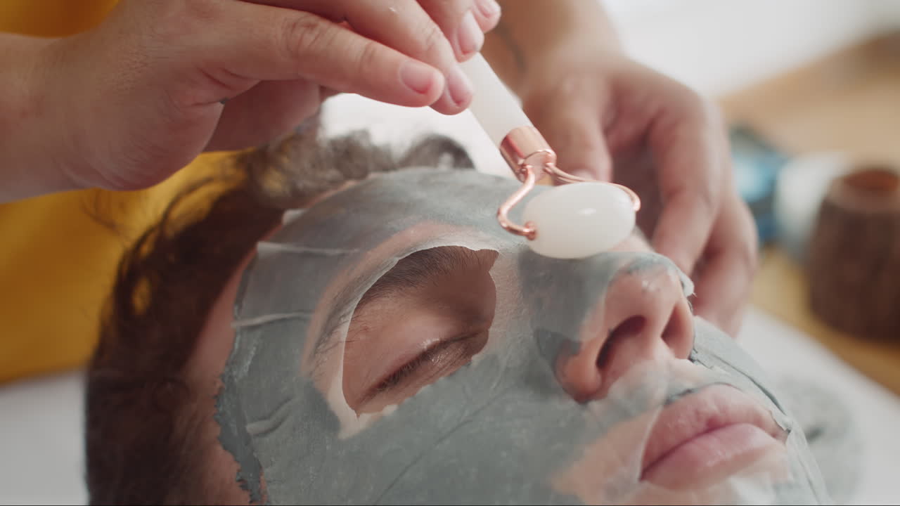 Male Client Enjoying Procedures with Roller and Sheet Mask on Face