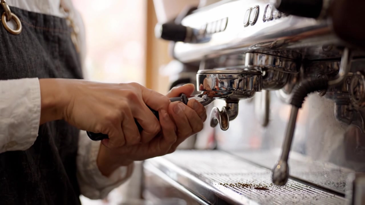 Preparare l'espresso perfetto: un barista prepara il caffè usando una macchina da caffè espresso di alta qualità in un accogliente ambiente da caffè.