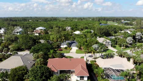 a low-level drone flight over a residential neighborhood in a tropical climate on a partly sunny day