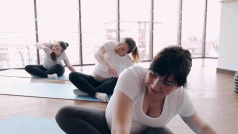 mujeres embarazadas están haciendo ejercicios en esteras con un instructor en un gimnasio