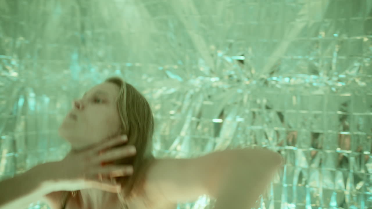 Female Dancer Performing under Colored Lights in Reflective Space