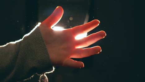 mujer joven, adolescente, juega con la luz moviendo su mano delicadamente, creando hermosos reflejos de luz
