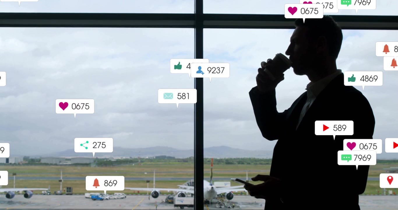 Businessman sipping cup scrolling phone at airport window sending social media icons swirling cloud