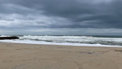 people gazing at the atlantic ocean's waves from a coastal cove at praia da costa nova, portugal