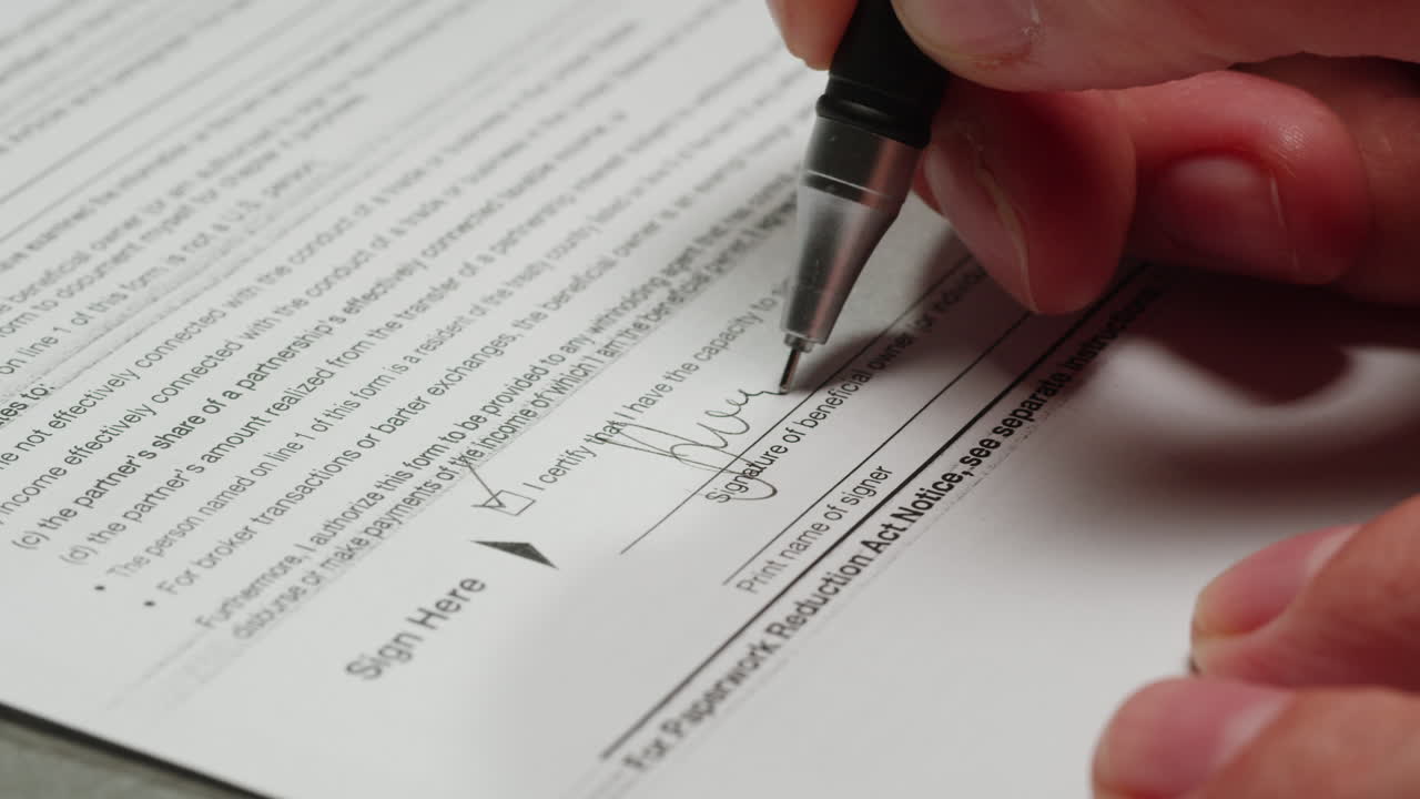 Close-Up of a Hand Signing an Official Document with a Pen