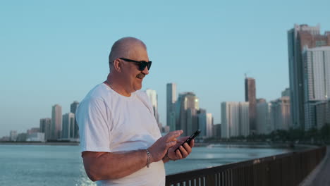 Bearded-senior-man-standing-outdoors-using-smartphone.-Retired-male-reading-news-chatting-with-his-children-via-mobile-phone.-Studying-city-map-app.-Lost-in-city-looking-for-right-direction.