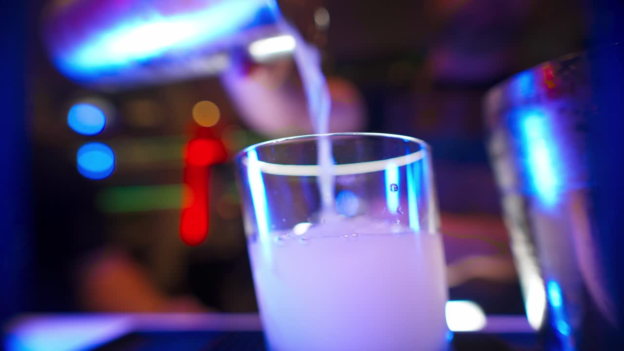 primo piano di un barista che riempie un bicchiere di ghiaccio con una bevanda che ha appena preparato