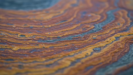 a close-up exploration of colorful patterns and textures in a geological surface, showcasing striking layers of orange, brown, and blue tones that capture natural beauty