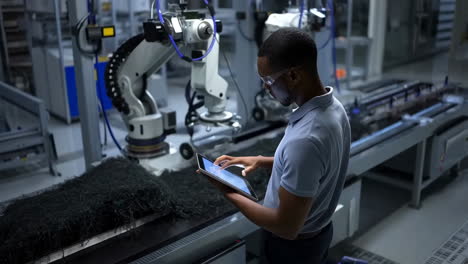 industrial worker supervising robotics with a tablet in a factory