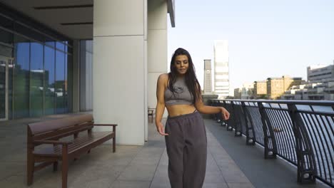 attractive young caucasian urban hip hop dancer with brown hair wearing sports clothing performing routine choreography mixture of different syles slow motion city environment