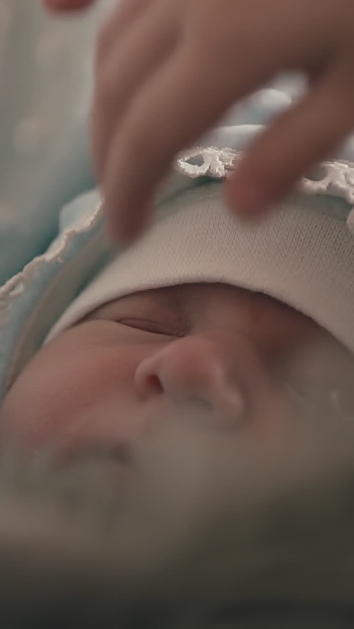 little girl in white sweater strokes carefully face of sleeping newborn brother on soft blanket at home closeup